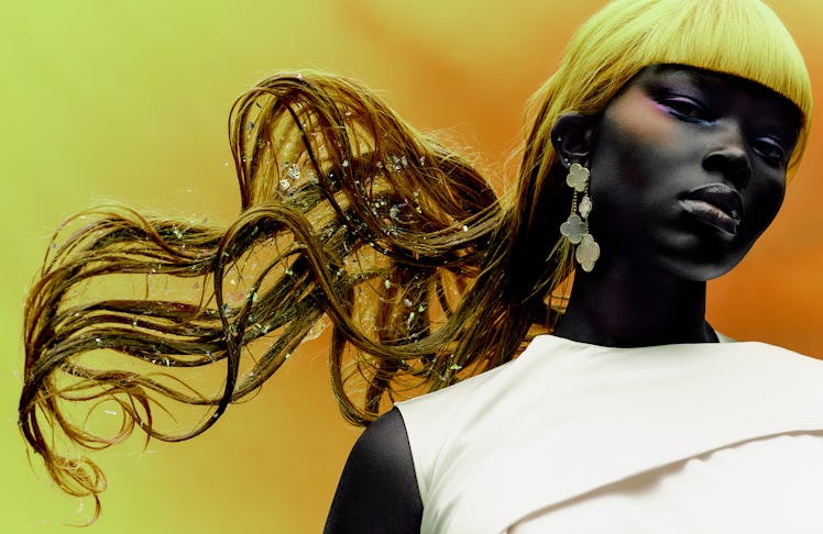 a person standing in front of a yellow wall with an artful blonde hairstyle